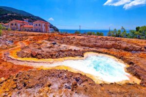 Φυσικές ιαματικές πηγές Αιδηψού με κόκκινα βράχια και ζεστό νερό να καταλήγει στη θάλασσα